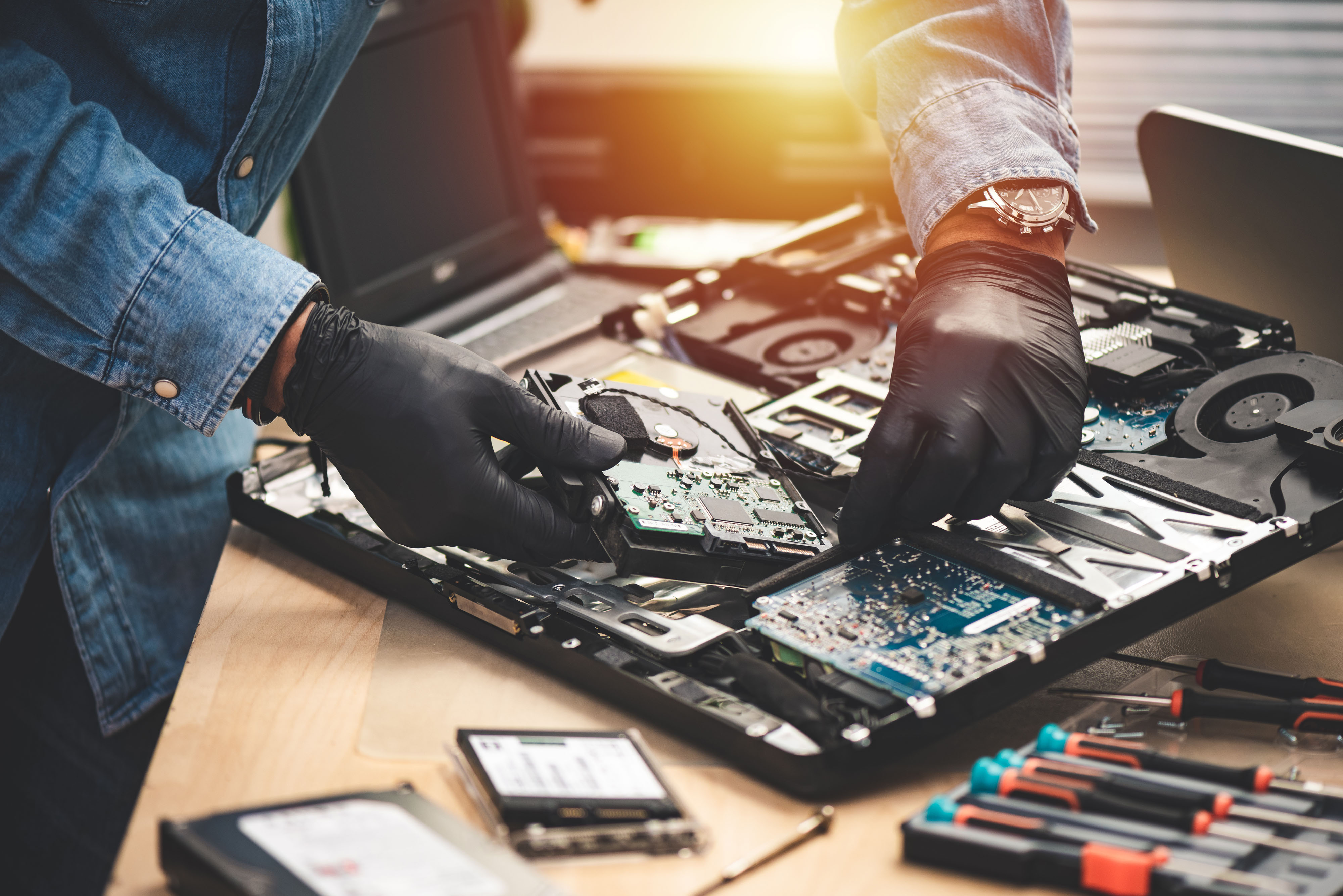 IT technician at a tidy desk helping a small business owner with a laptop repair, warm office lighting, professional and approachable